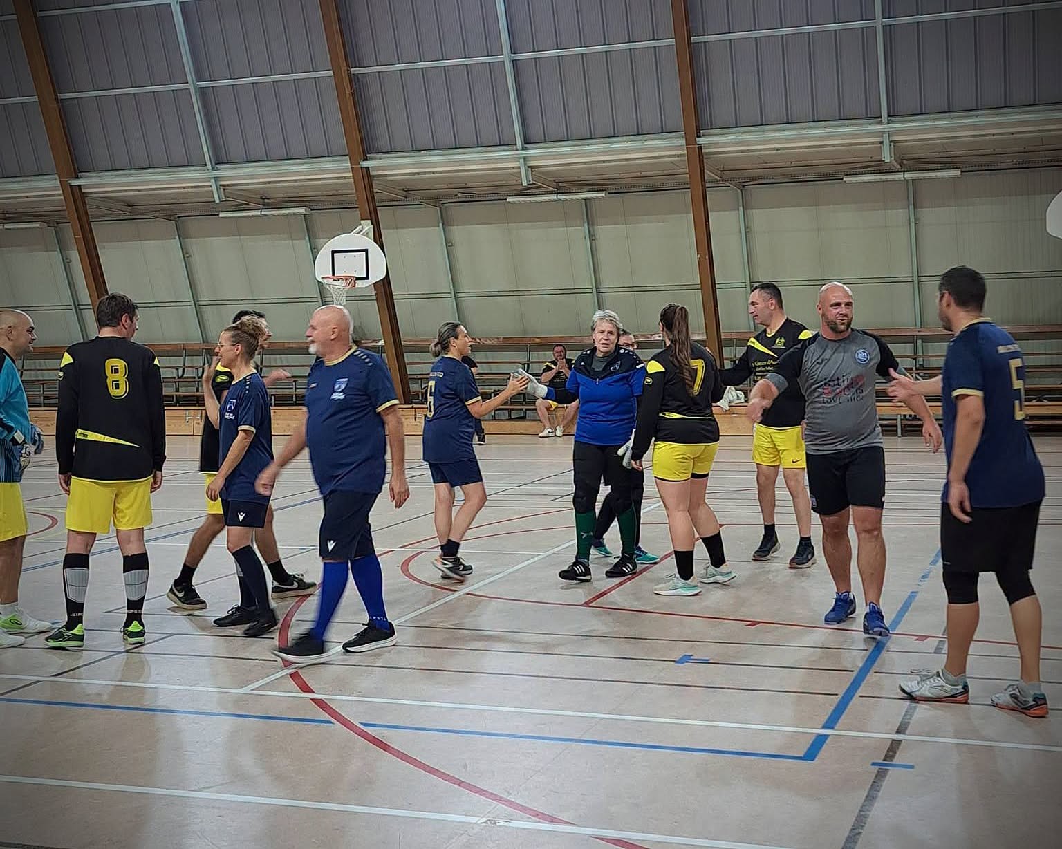 Les équipes échangent des salutations sur le terrain du gymnase COSEC