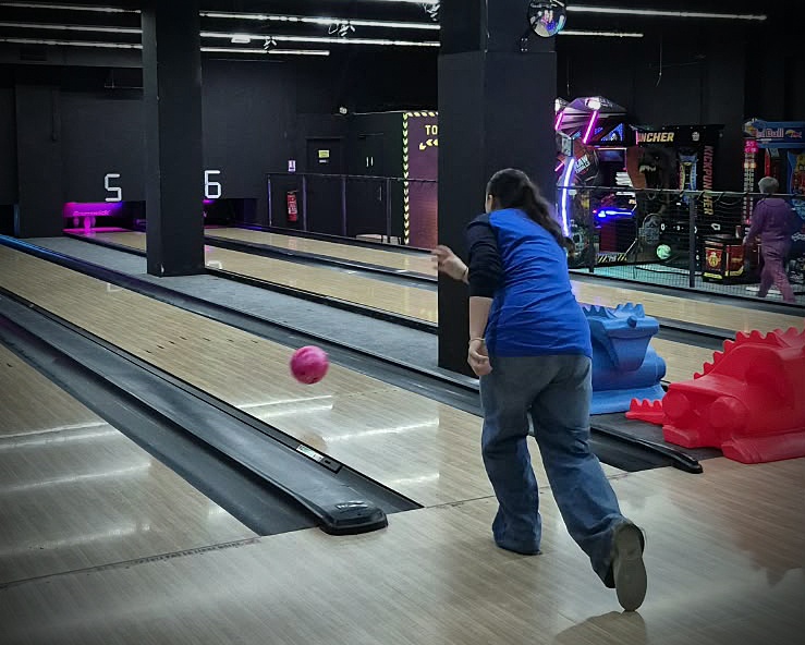 Une participante lance sa boule sur la piste de bowling
